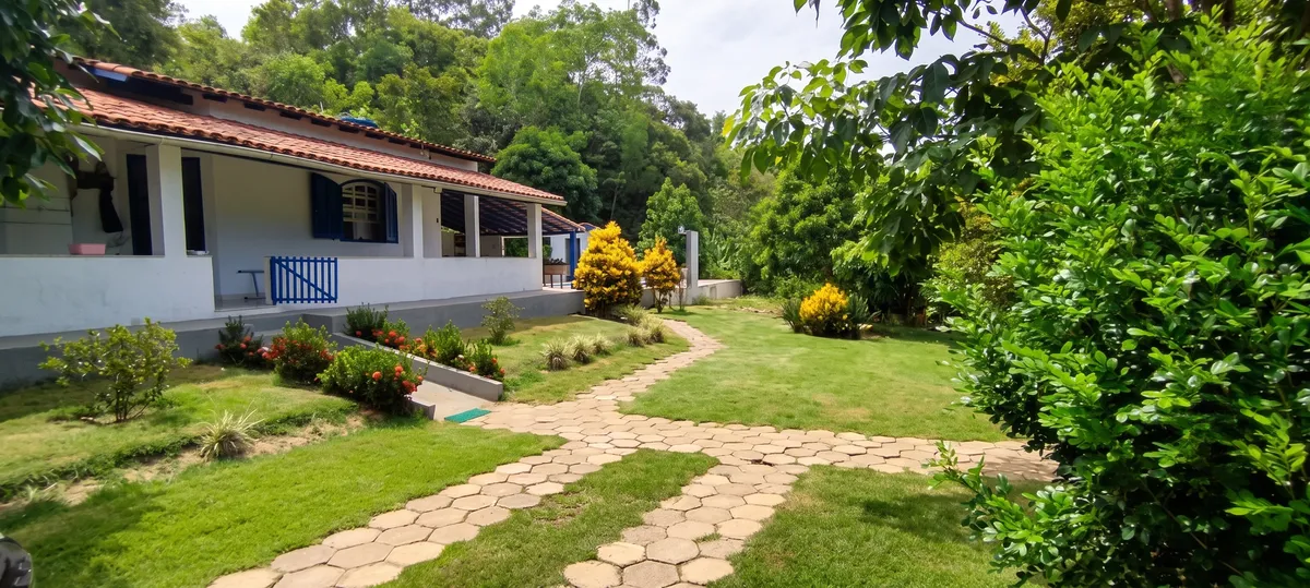 Fachada do casarão colonial com caminho de pedras e jardim florido no Sítio Canto da Seriema